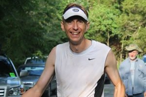 Runner wears a white shirt, white visor smiles at camera
