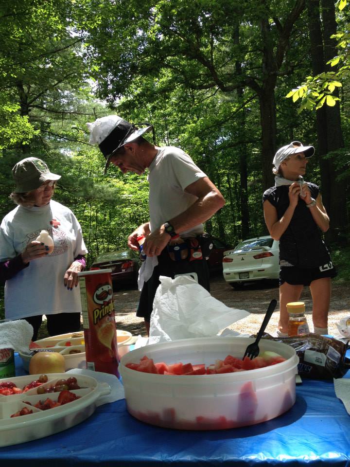 runner with hat on packs his supplies at aid station