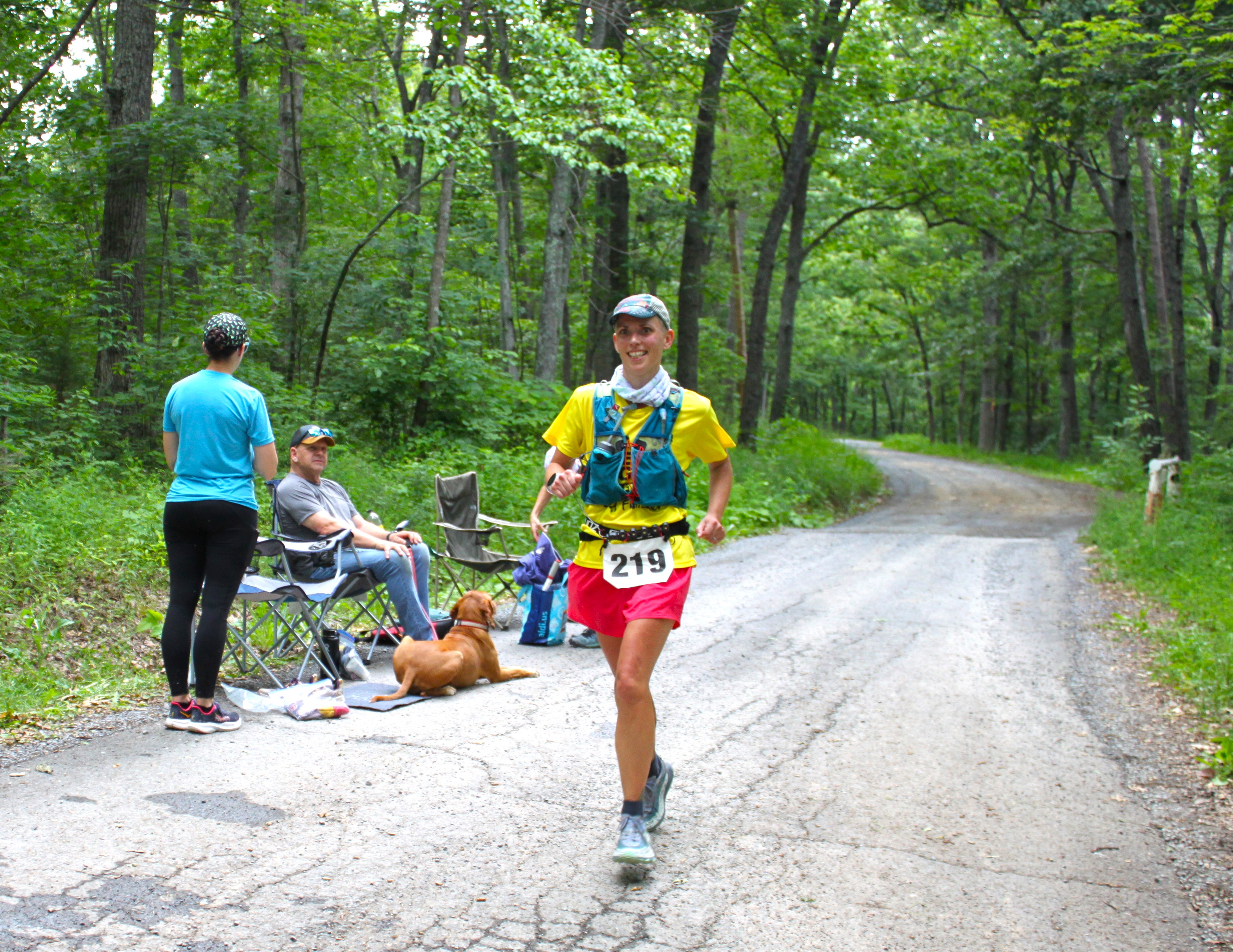 Female runner, wearing bib 219. smiling
          at camera. Pit crew off to the side.