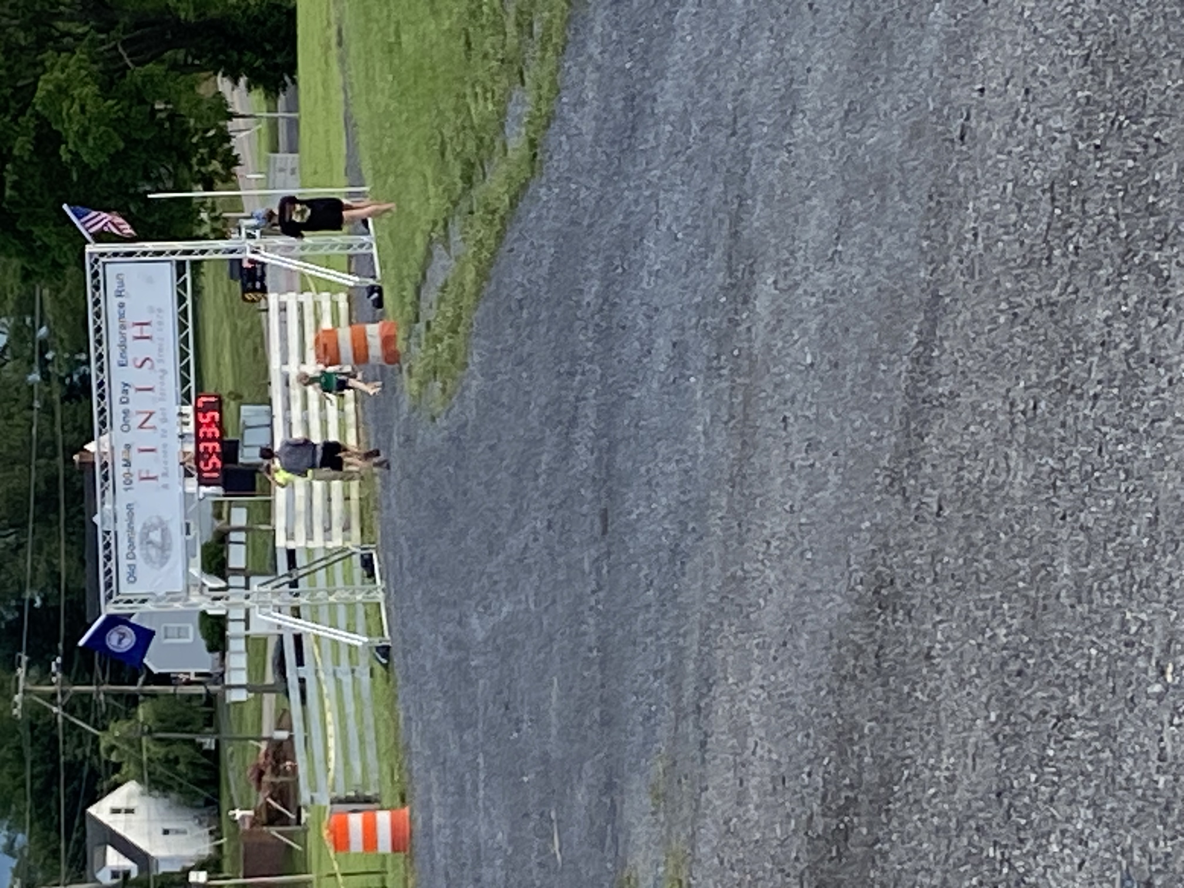 Finish Line in the Distance.
          Runner crossing under with a time of 15:33