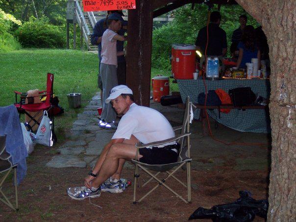 Runner sits in a chair to adjust their shoe at an aid station